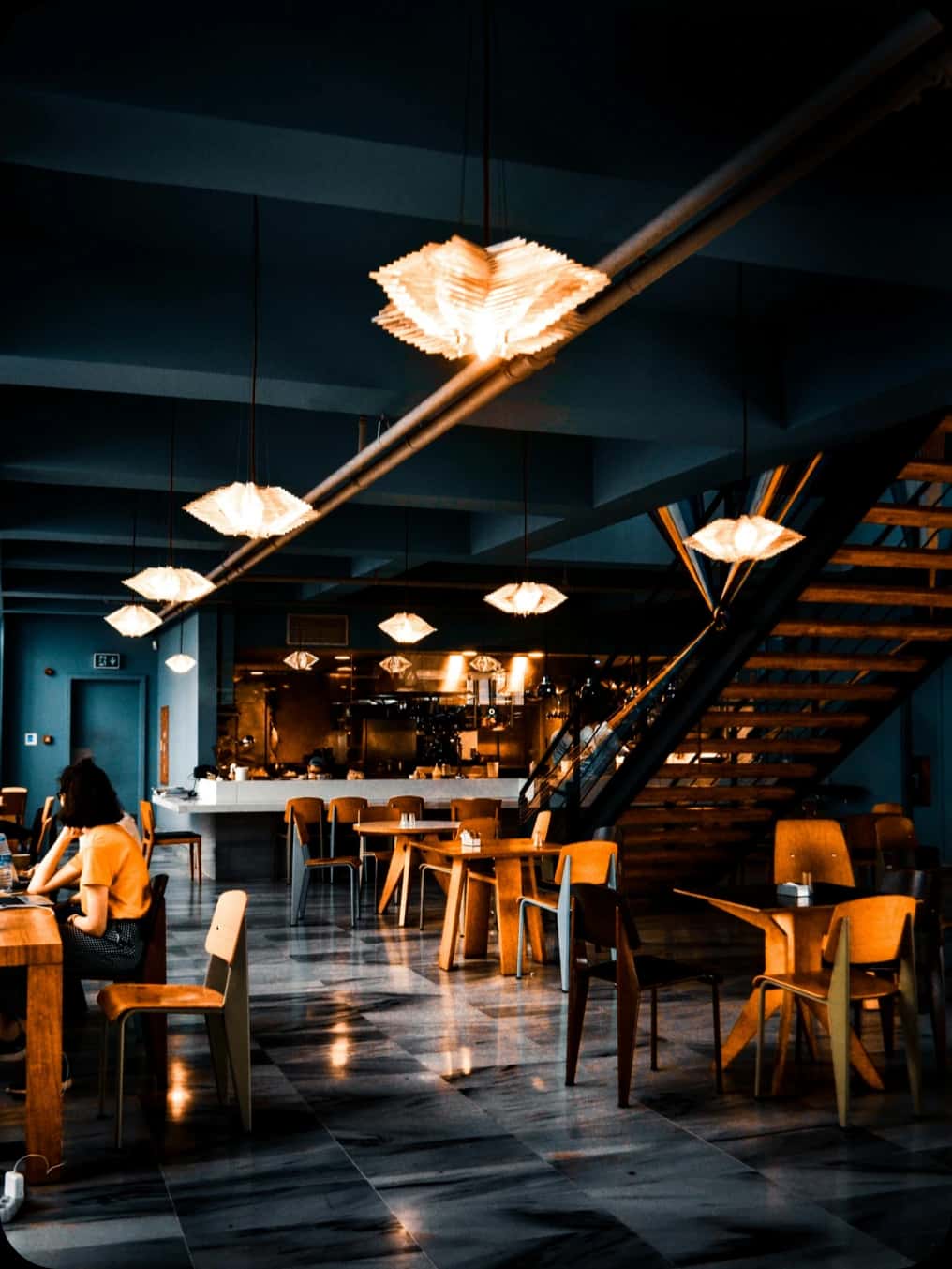 Interijer restorana sa stolovima i visećim svjetiljkama